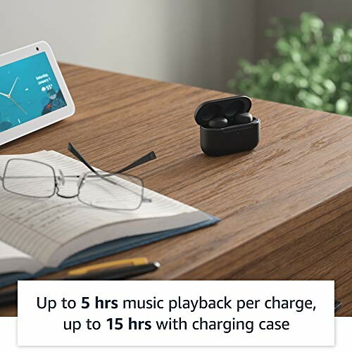 Wireless earbuds in charging case on desk with glasses, notebook, and smart display.